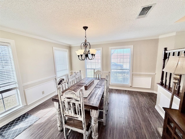 dining space with a wainscoted wall, visible vents, ornamental molding, dark wood-style floors, and an inviting chandelier