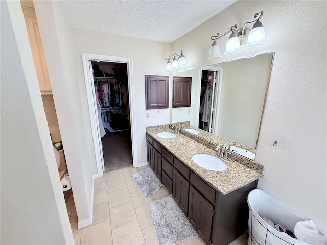 full bath with a textured ceiling, a spacious closet, and a sink