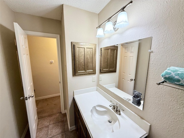 bathroom with a textured ceiling, baseboards, vanity, and tile patterned floors