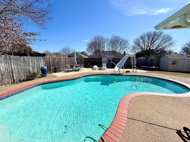 view of pool featuring a storage shed, a fenced in pool, a patio, a fenced backyard, and a water slide