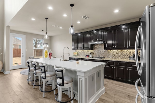 kitchen with visible vents, appliances with stainless steel finishes, dark cabinetry, under cabinet range hood, and a sink