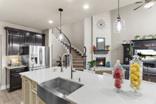 kitchen with open floor plan, a fireplace, stainless steel refrigerator with ice dispenser, and a sink