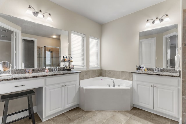 full bathroom with a sink, two vanities, a shower stall, and a garden tub