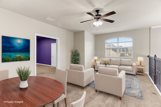 living area featuring a ceiling fan, visible vents, and light colored carpet