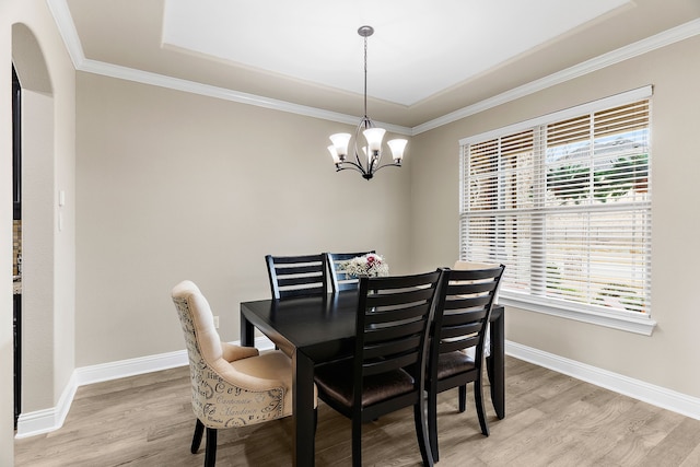 dining area featuring baseboards, arched walkways, ornamental molding, light wood-type flooring, and a chandelier