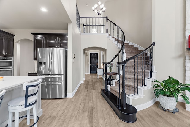 kitchen with stainless steel appliances, arched walkways, light wood-type flooring, and light countertops