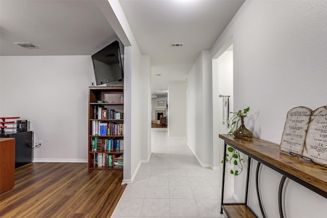 hallway featuring visible vents, baseboards, and light tile patterned floors