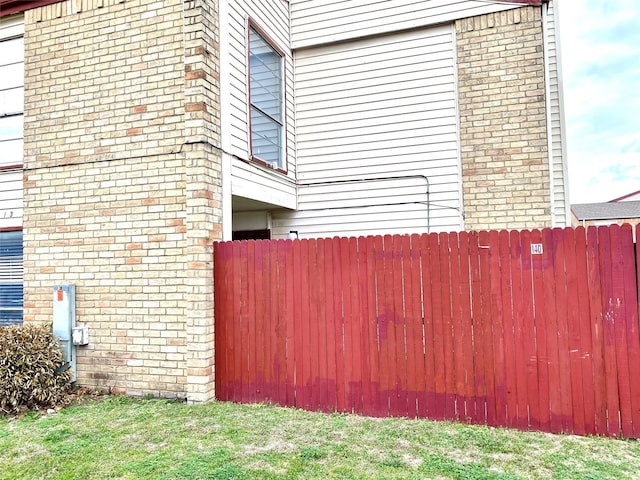 view of side of home with brick siding and fence