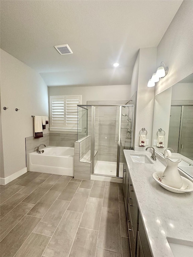 bathroom with a sink, visible vents, a shower stall, a bath, and double vanity