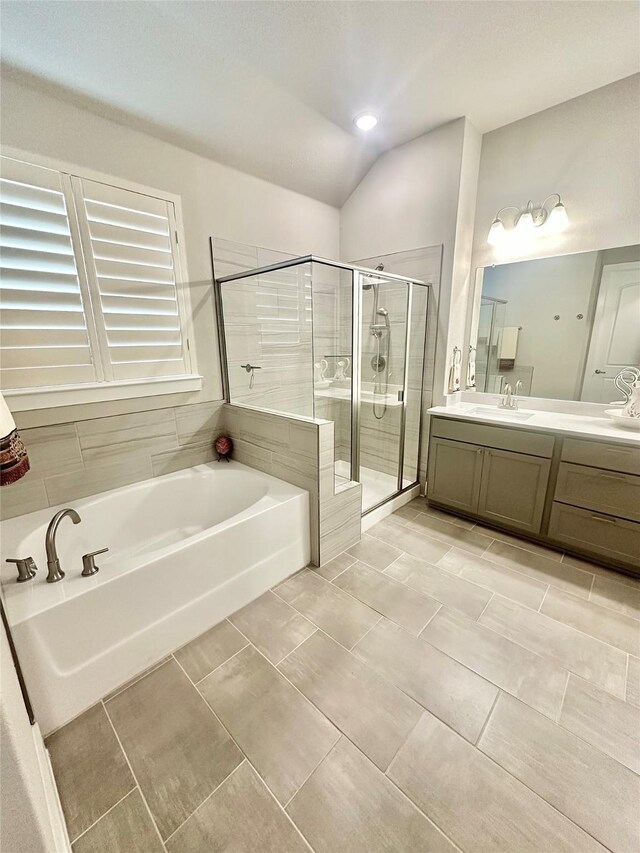 bathroom featuring a stall shower, vaulted ceiling, a bath, and vanity