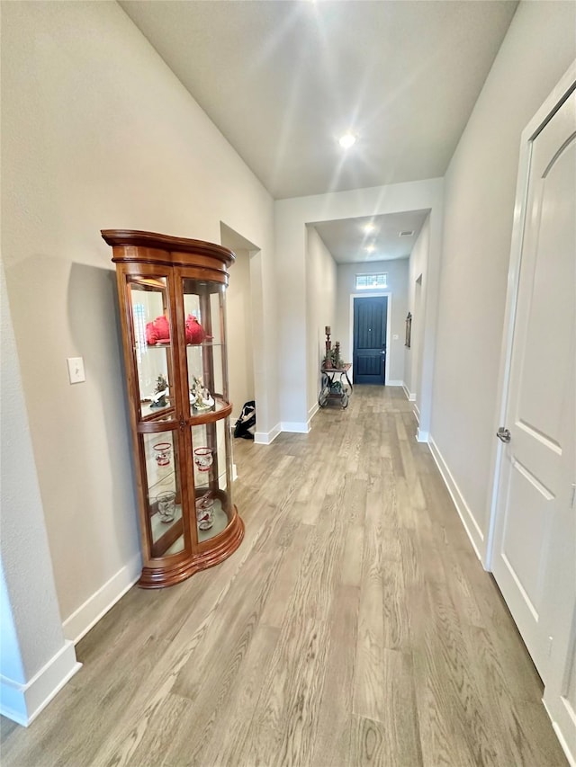 corridor with light wood-style flooring and baseboards