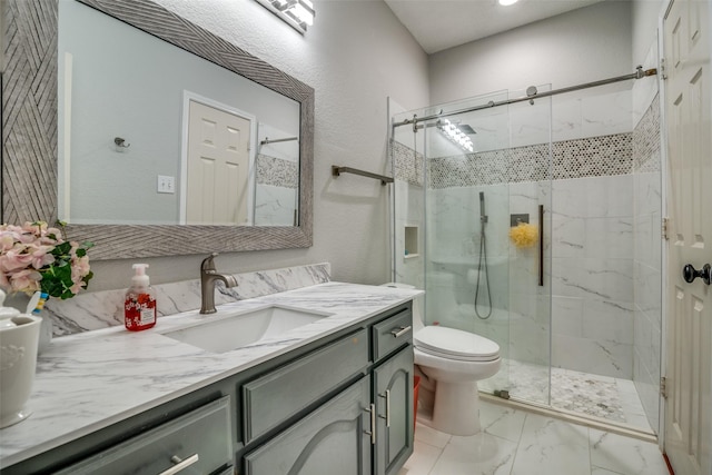 bathroom with a textured wall, toilet, vanity, marble finish floor, and a marble finish shower