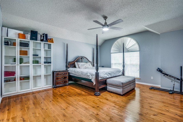 bedroom with baseboards, a ceiling fan, vaulted ceiling, a textured ceiling, and light wood-style floors