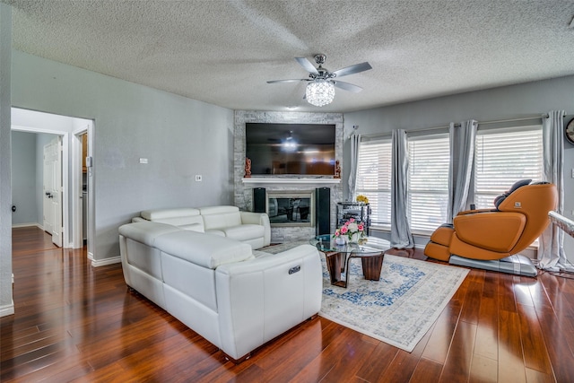 living room featuring baseboards, dark wood finished floors, ceiling fan, a textured ceiling, and a fireplace