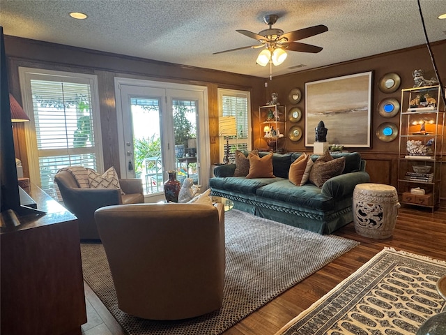 living area with ceiling fan, a textured ceiling, and wood finished floors