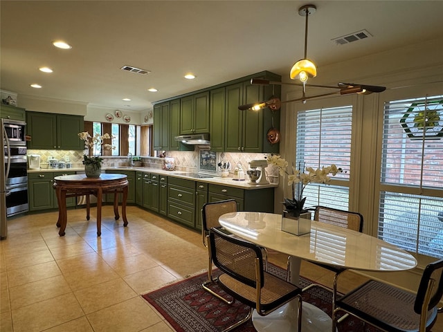 kitchen featuring under cabinet range hood, visible vents, light countertops, and green cabinetry