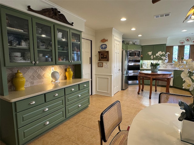 kitchen with visible vents, light countertops, glass insert cabinets, appliances with stainless steel finishes, and green cabinetry