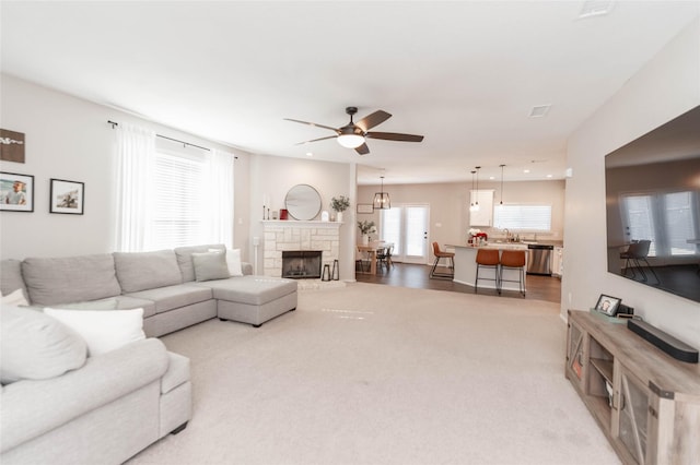 carpeted living room with recessed lighting, visible vents, a ceiling fan, a sink, and a stone fireplace