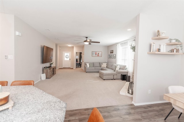 living area with wood finished floors, a ceiling fan, and baseboards