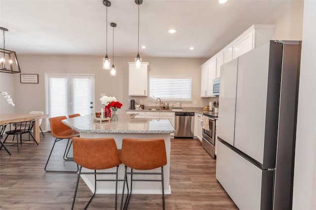 kitchen featuring pendant lighting, appliances with stainless steel finishes, dark wood-style flooring, and white cabinets