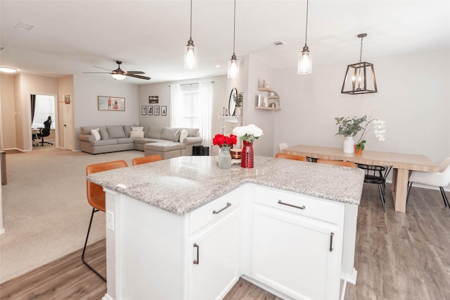 kitchen with pendant lighting, open floor plan, white cabinets, and light stone countertops