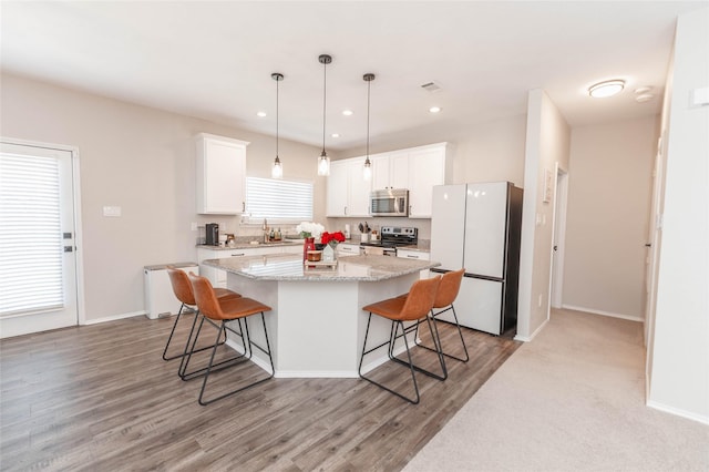 kitchen featuring a sink, stainless steel appliances, a kitchen island, and white cabinetry