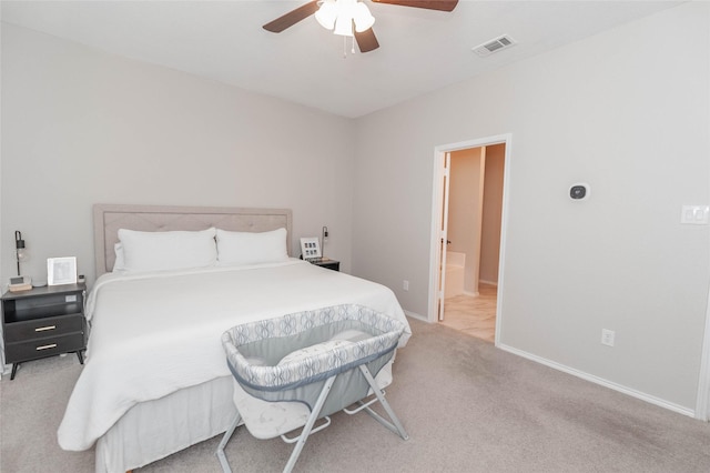 bedroom with light carpet, baseboards, visible vents, a ceiling fan, and ensuite bathroom