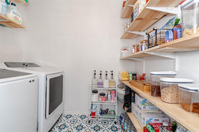 washroom featuring laundry area, baseboards, washing machine and clothes dryer, and light tile patterned floors