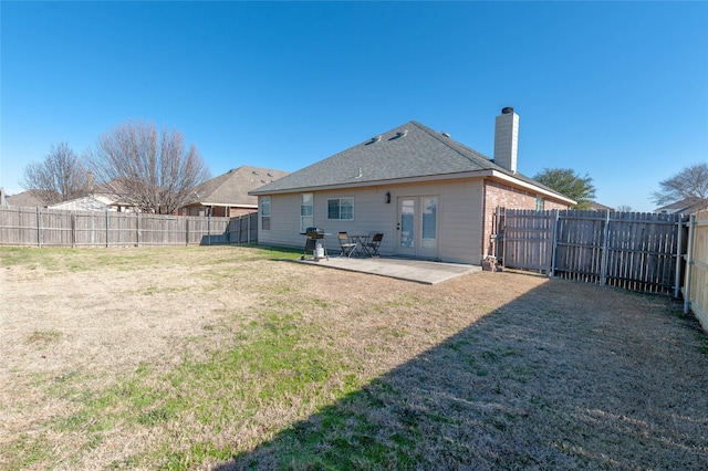 rear view of property with a patio, a fenced backyard, french doors, a lawn, and a chimney