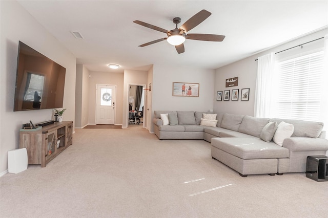 living area featuring light carpet, baseboards, and a ceiling fan