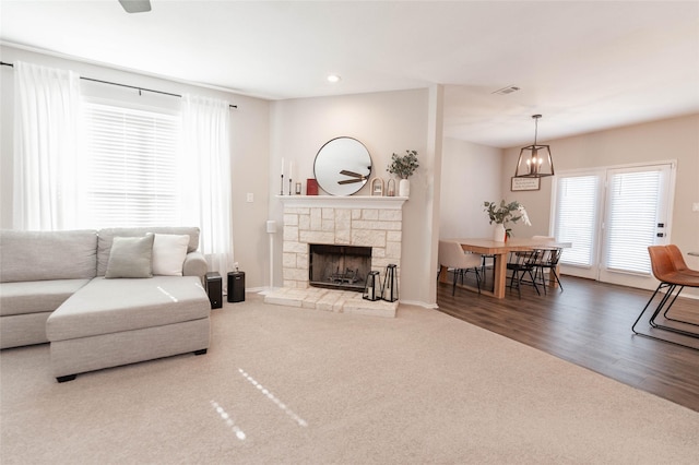 living area featuring a stone fireplace, recessed lighting, carpet floors, wood finished floors, and visible vents