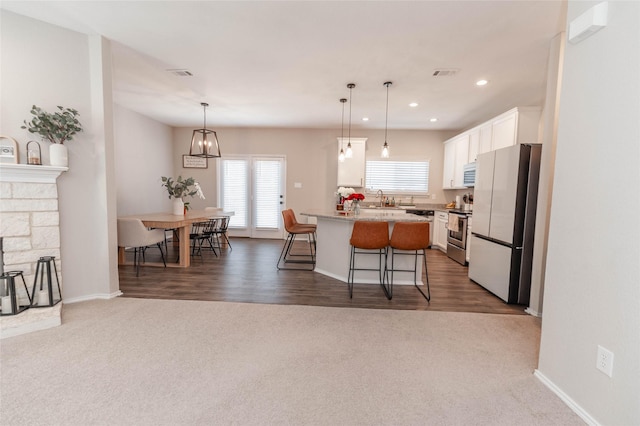 kitchen with a center island, hanging light fixtures, white cabinets, white appliances, and a kitchen breakfast bar