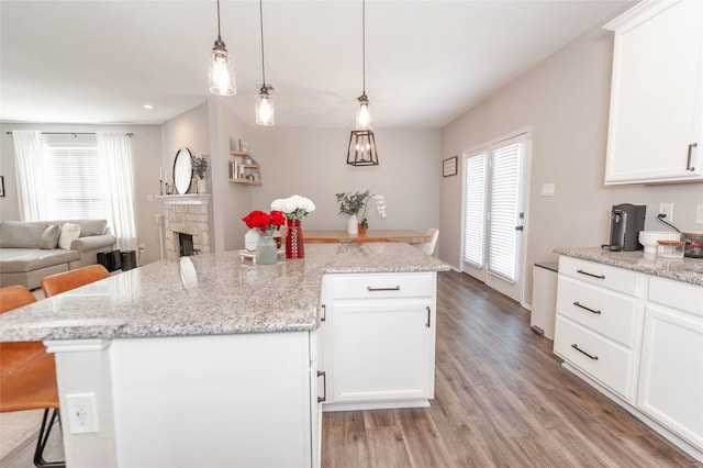 kitchen with a breakfast bar, hanging light fixtures, light wood-style floors, open floor plan, and white cabinets