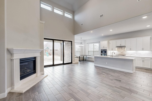 unfurnished living room featuring a wealth of natural light, wood tiled floor, a glass covered fireplace, and a sink