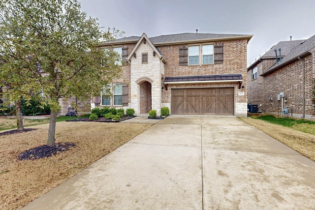 view of front of property featuring an attached garage, central AC, brick siding, stone siding, and concrete driveway