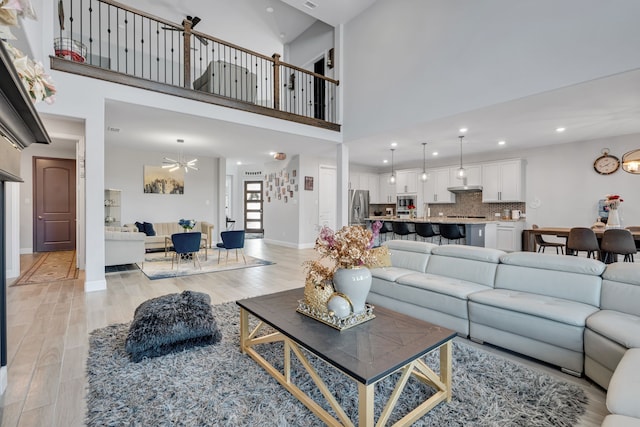 living room featuring baseboards, recessed lighting, light wood-style flooring, and a notable chandelier