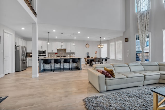 living area with plenty of natural light, a towering ceiling, and light wood-style floors