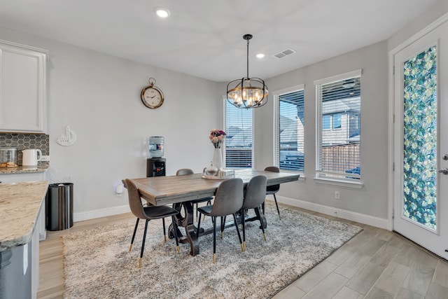 dining room with light wood-type flooring, visible vents, baseboards, and an inviting chandelier