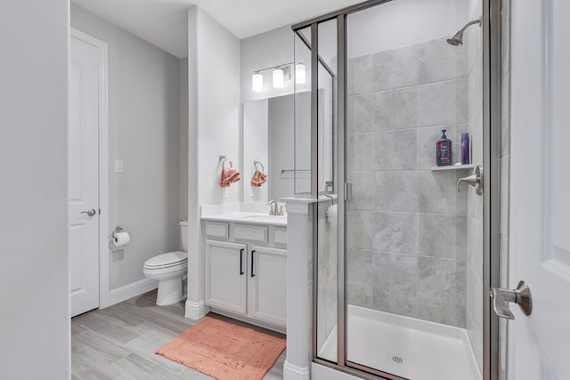 full bathroom featuring toilet, wood finished floors, vanity, baseboards, and a shower stall