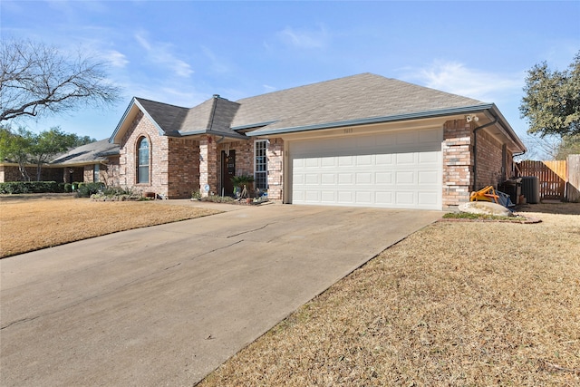 ranch-style house featuring brick siding, concrete driveway, an attached garage, central AC unit, and fence