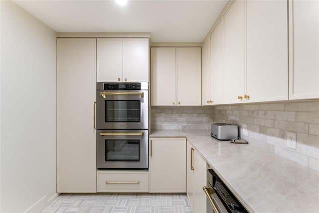 16912 Park Hill Dr, Dallas, TX 75248 - kitchen featuring double oven, backsplash, and white cabinetry