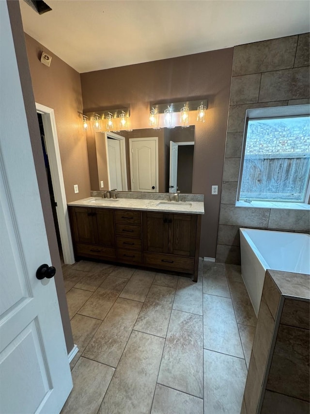 full bath featuring a tub to relax in, tile patterned floors, a sink, and double vanity