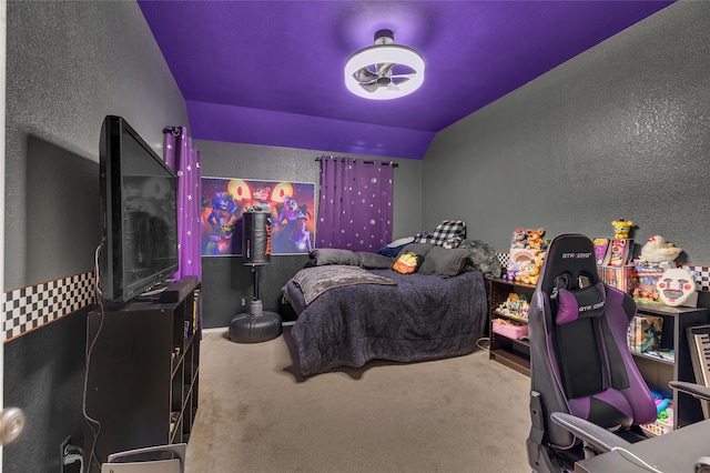 bedroom with lofted ceiling, a textured wall, and carpet flooring