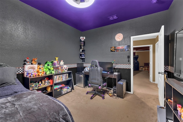 carpeted bedroom with visible vents and a textured wall