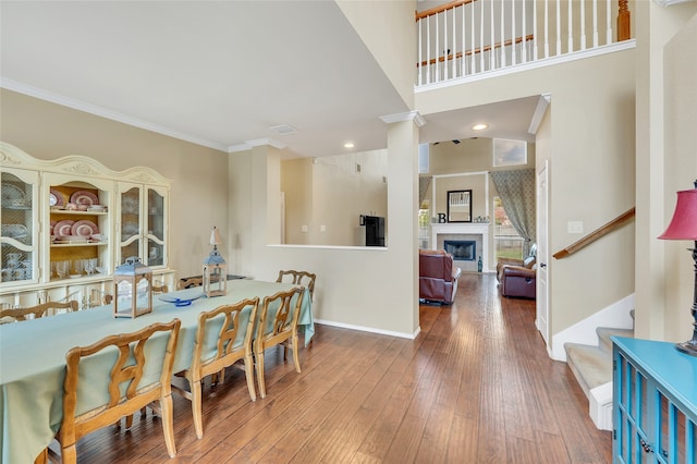 dining room featuring visible vents, a tile fireplace, hardwood / wood-style flooring, ornamental molding, and stairs