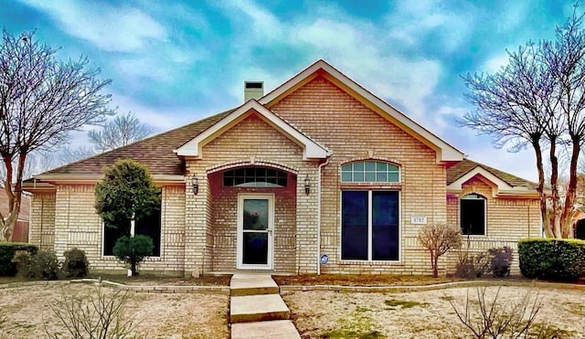 view of front of home featuring brick siding and a chimney