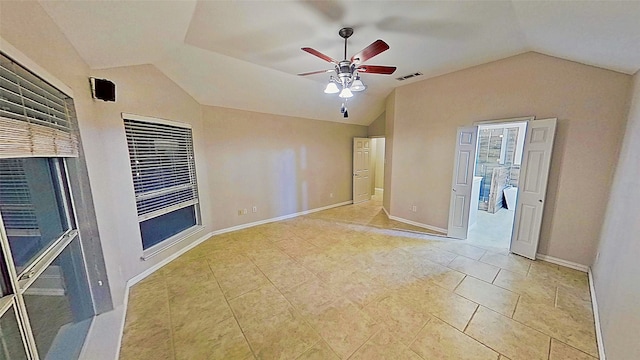 spare room with vaulted ceiling, ceiling fan, visible vents, and baseboards