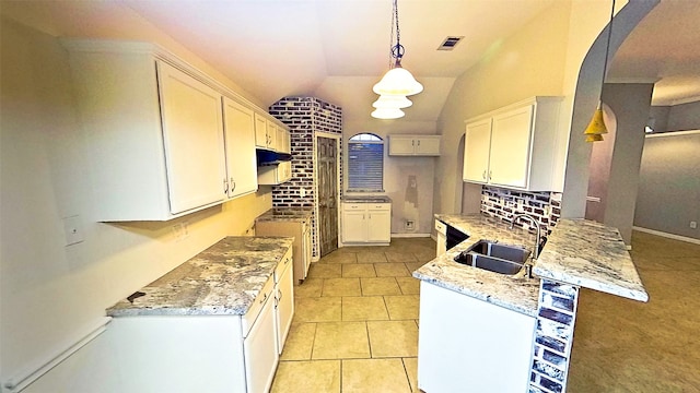 kitchen with arched walkways, pendant lighting, white cabinetry, a sink, and light stone countertops