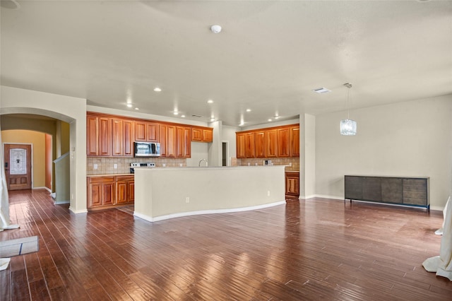 kitchen with open floor plan, light countertops, stainless steel microwave, and an island with sink