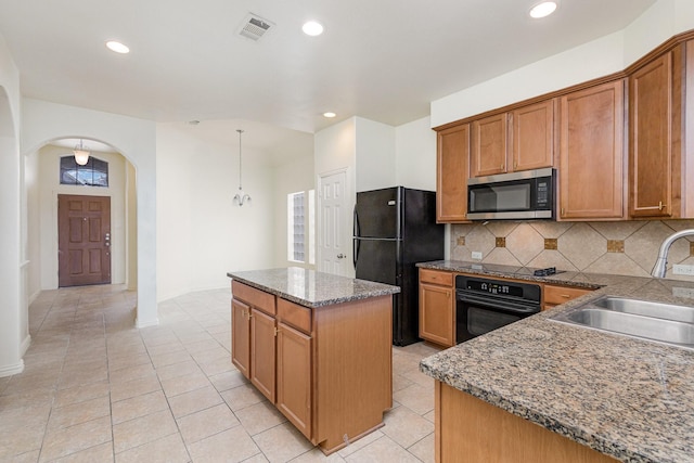 kitchen with arched walkways, a sink, a center island, brown cabinets, and black appliances